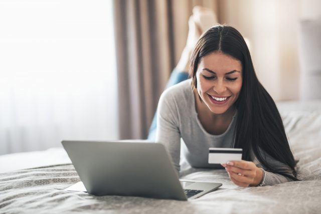 woman smiling while using her credit card