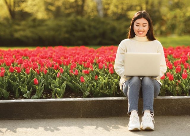 person-on-laptop-in-the-spring-with-tuilips-blossoming-640x460