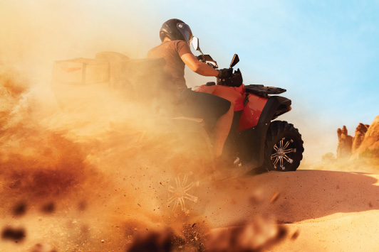 ATV rider kicking up sand