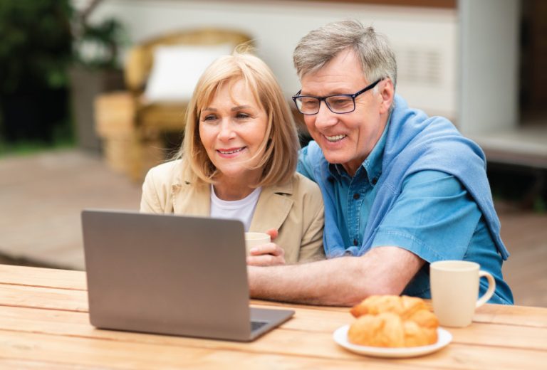 older couple looking at a laptop together during breakfast