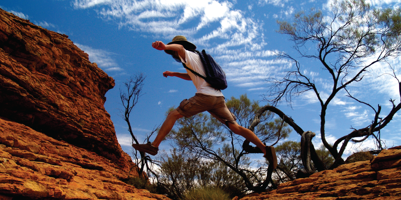 person jumping over a rock formation