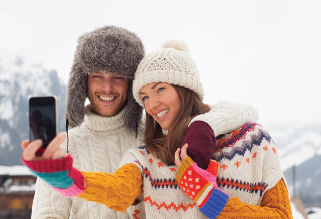 winter-couple-in-sweaters-and-warm-hats-and-phone