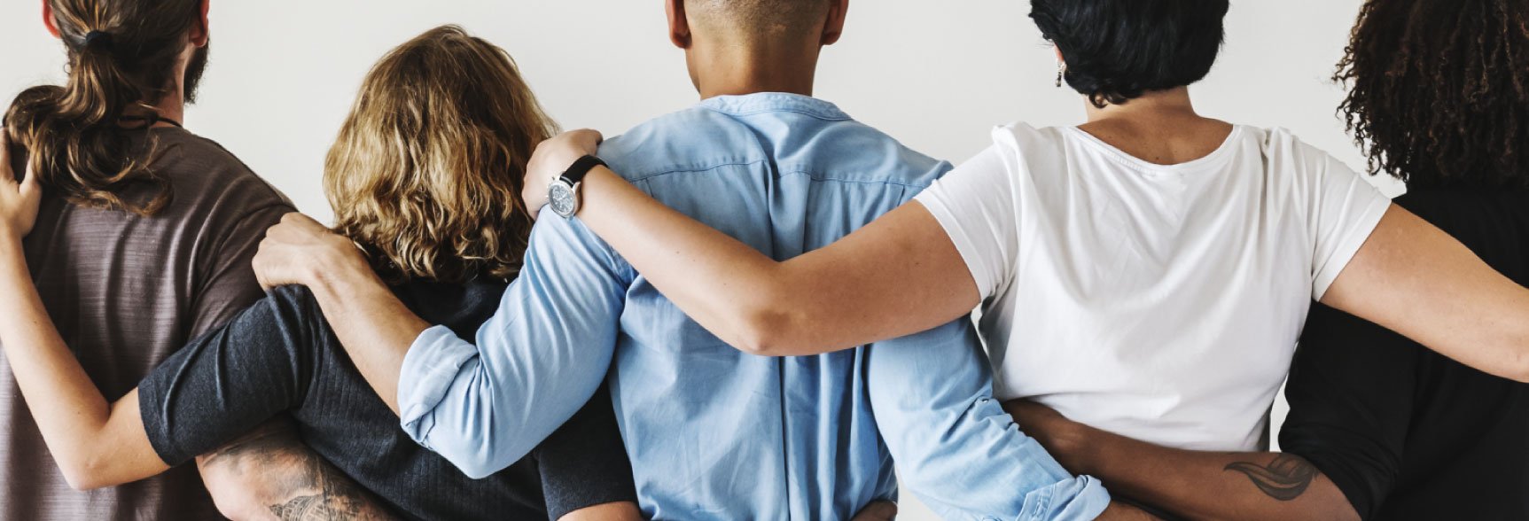 Group of people standing arm and arm next to each other