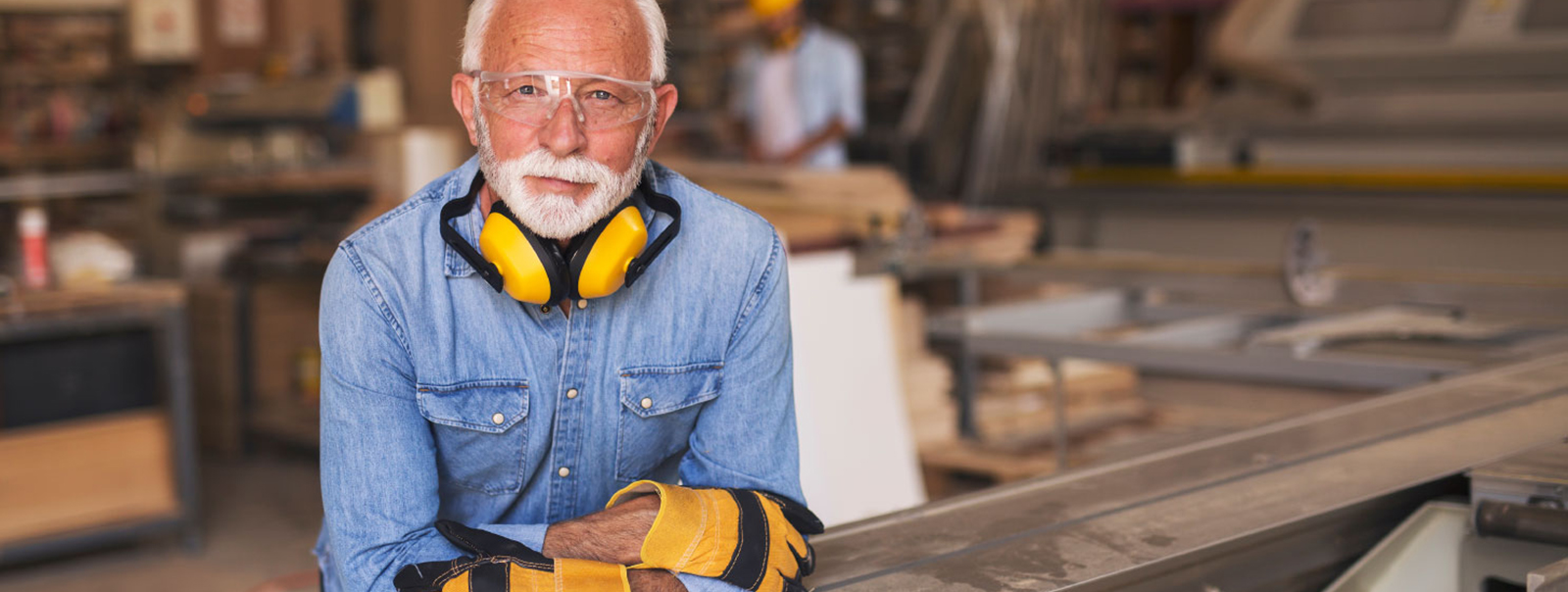 Dedicated business owner working in his woodshop with yellow gloves and safety glasses