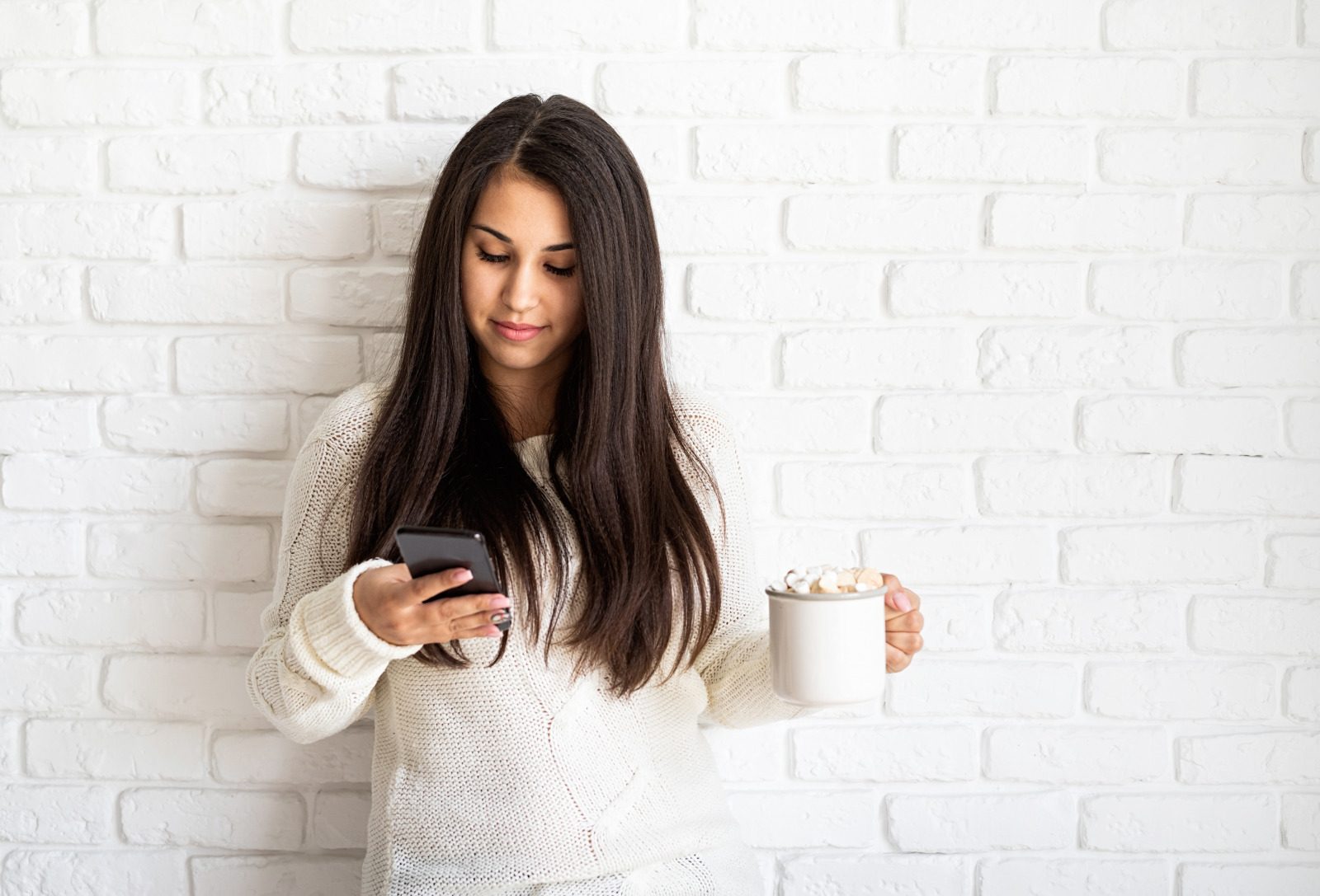person with white sweater looking at phone
